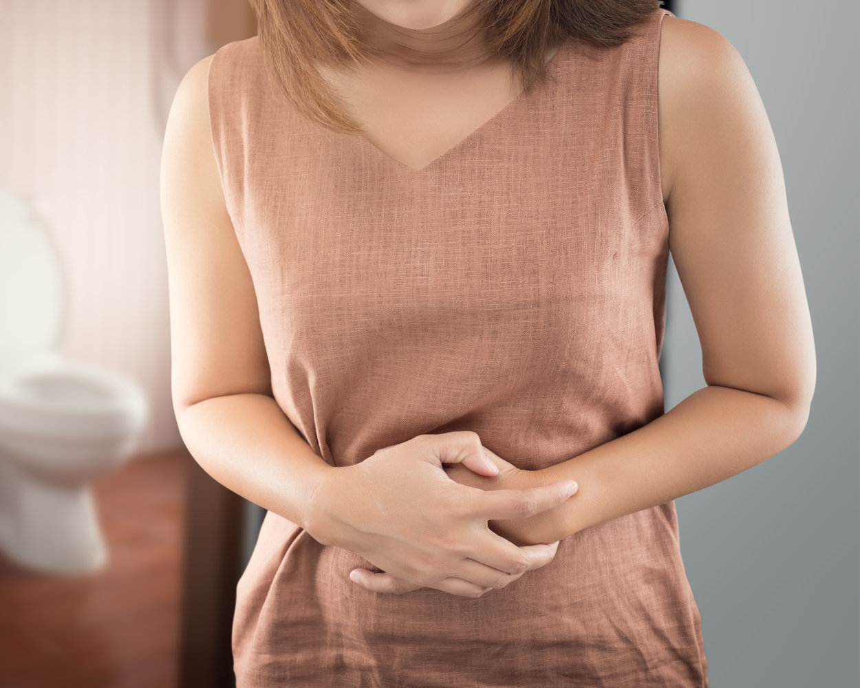 Frau greift sich auf ihren Bauch, weil der harte Stuhlgang schmerzt.